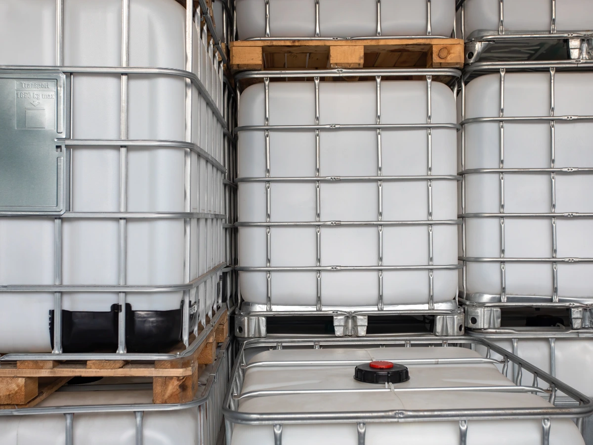 White intermediate bulk containers (IBCs) in metal cages stacked for liquid storage.